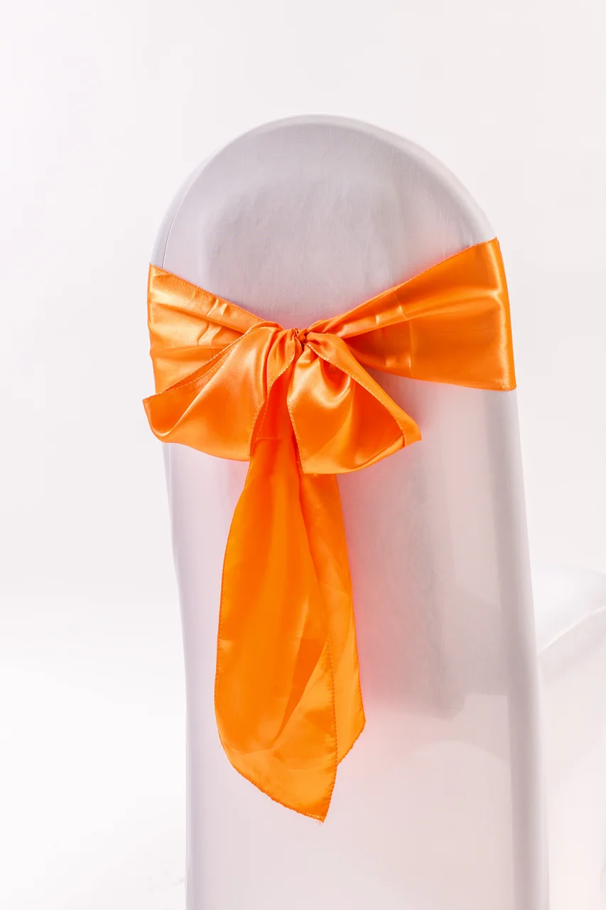Orange chair sash tied in a bow on a white covered chair