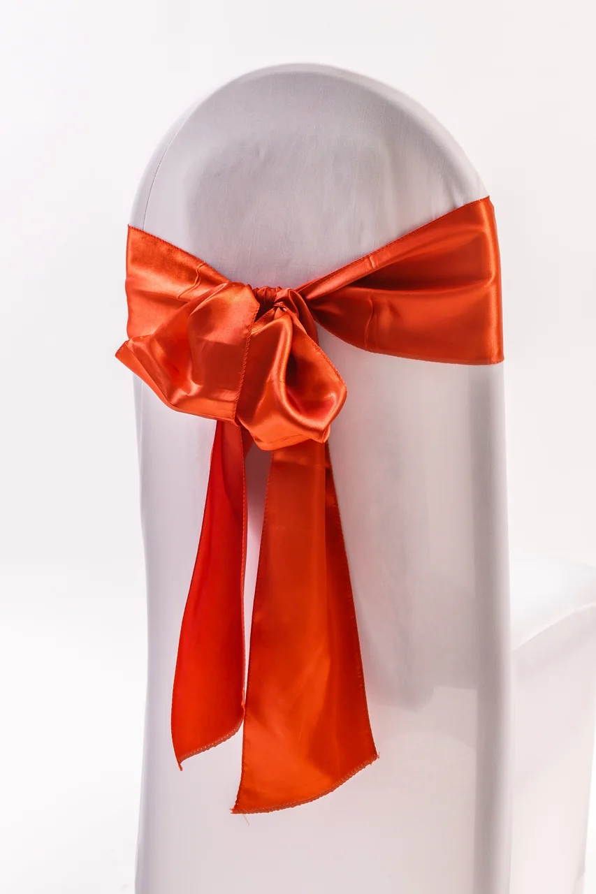 Rust orange chair sash tied in a bow on a white covered chair